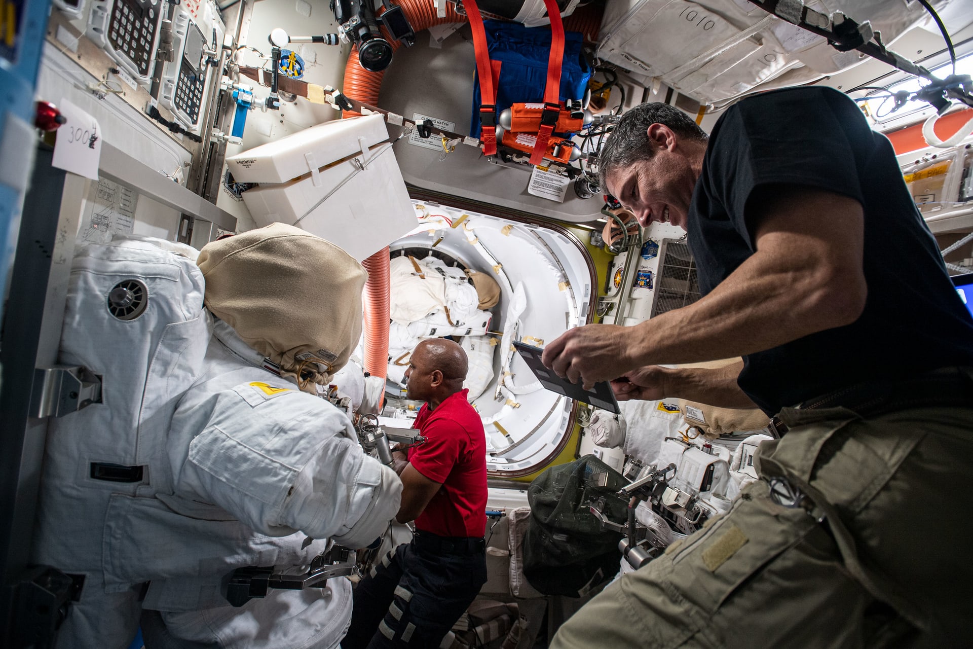 Astronauts working with scientific equipment inside the International Space Station laboratory module